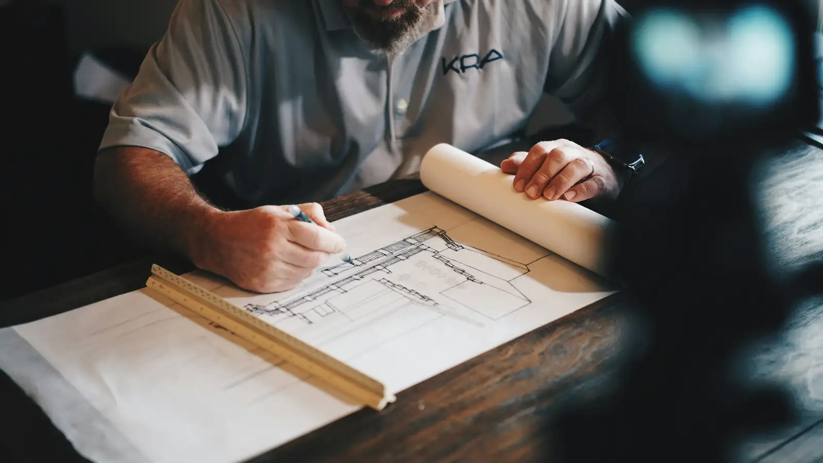 An architect drafting a plan with a pencil and scale ruler