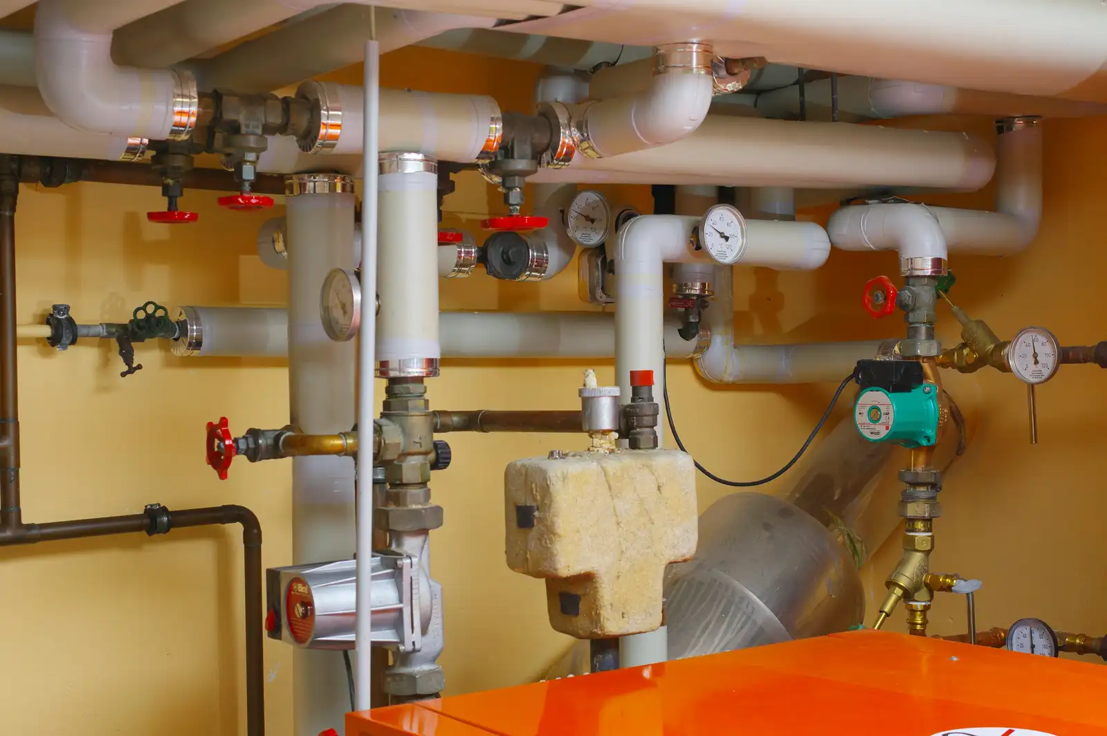 A boiler room: pipes, valves, gauges, a pump and the boiler