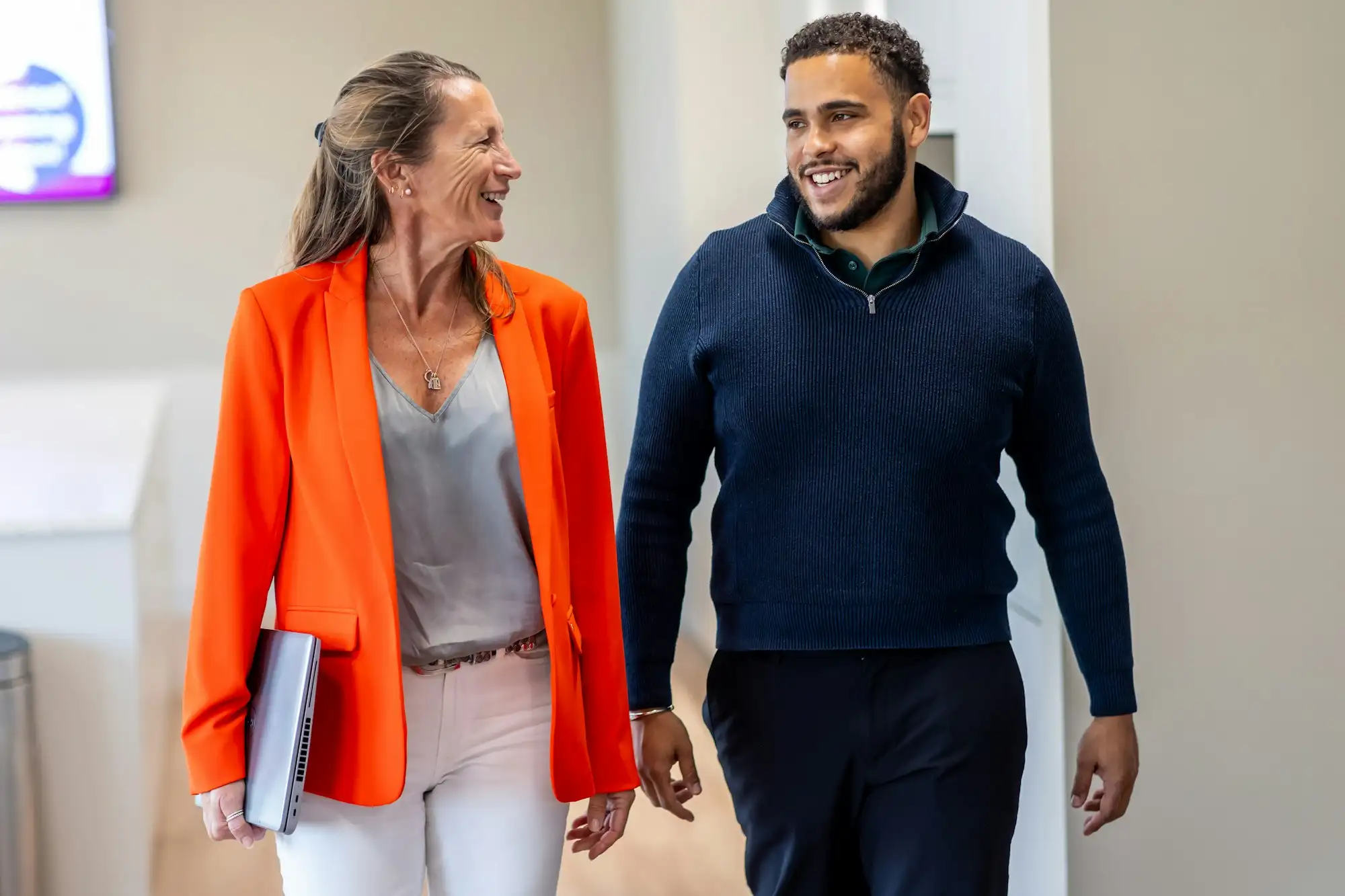 Two people walking through an office, talking