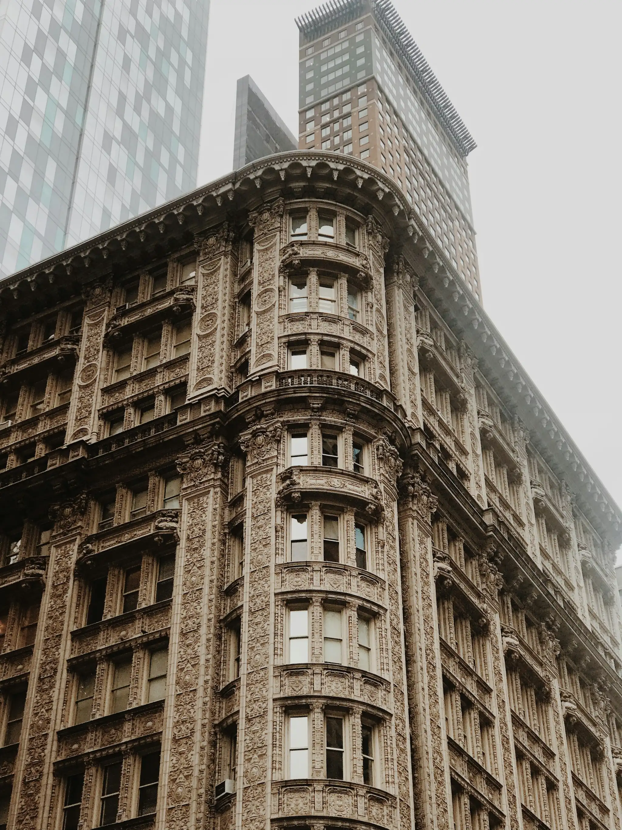 An ornate stone facade with cornices, seen from the sidewalk