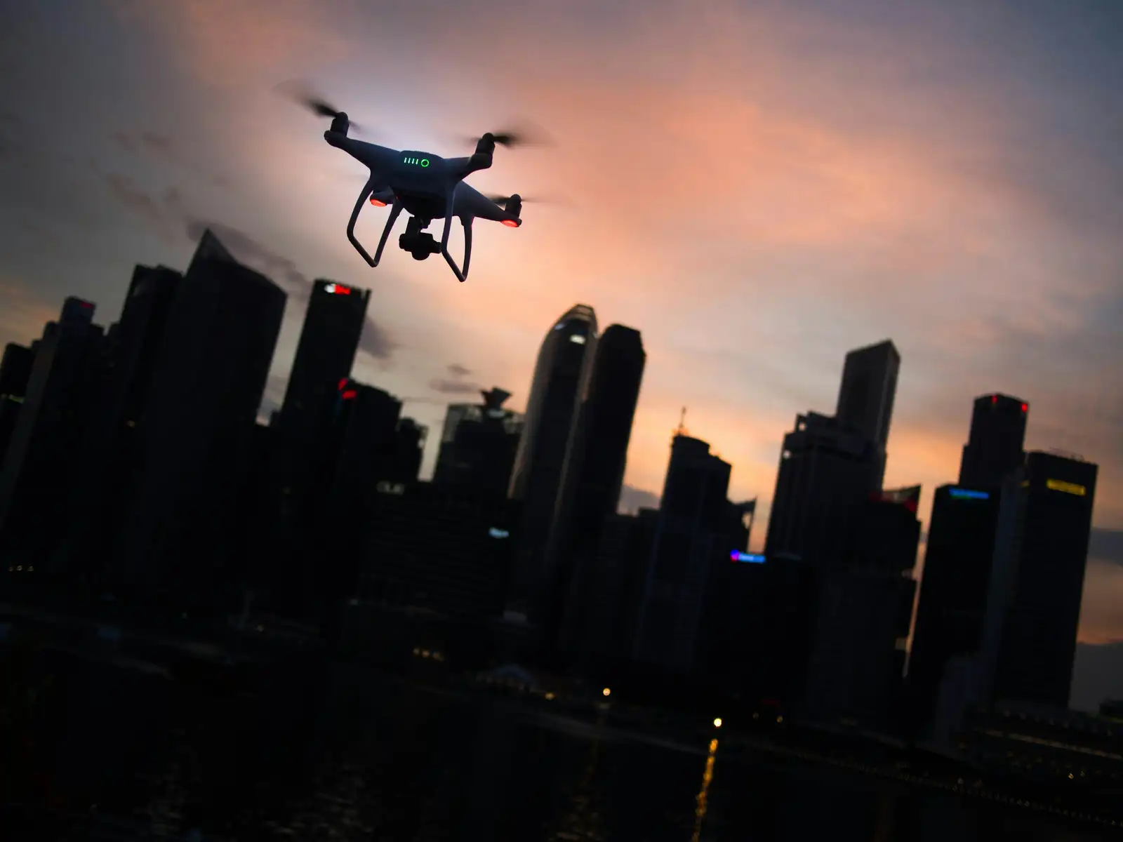 A drone flying near city towers at dusk