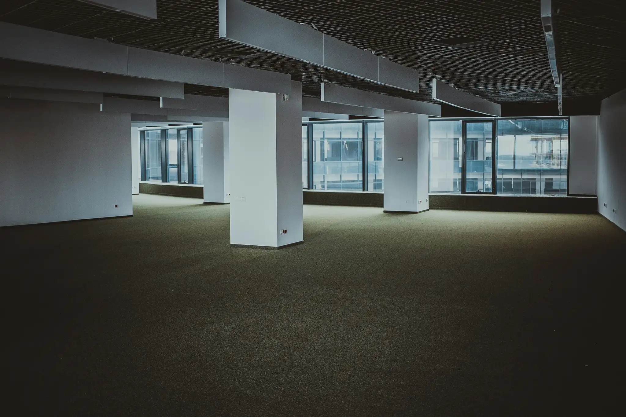 An empty office floor with columns and tall windows