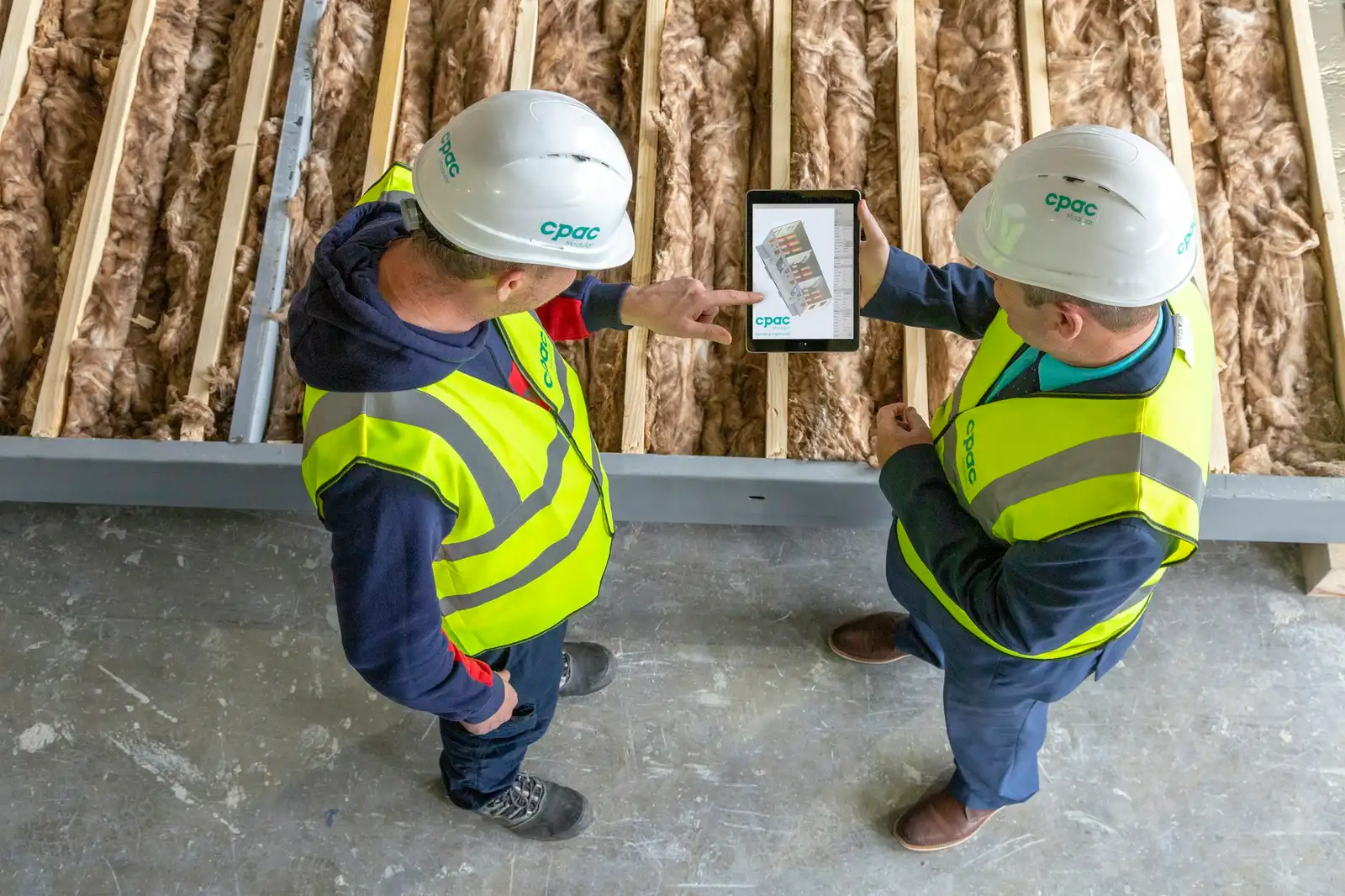 Two people in hard hats reviewing plans on a tablet during a fit-out
