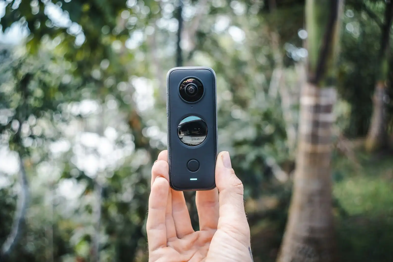 A hand holding a pocket 360 camera