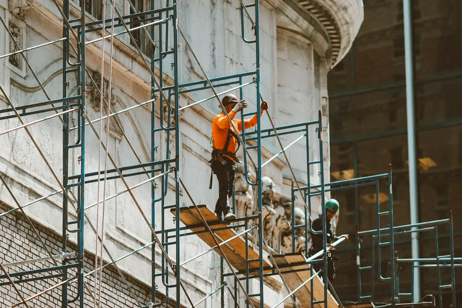 Workers on scaffolding against an ornate stone facade